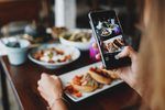 An image of an influencer taking a photo of food at a restaurant.